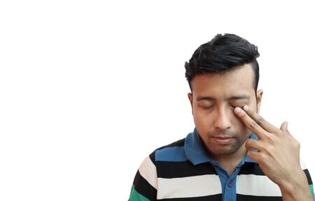 indonesian guy weeping in depressed mood with finger on eye in white background with copy space for text.Sad mood conceptの写真素材