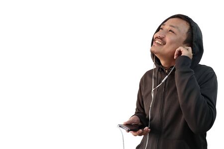 a japanese man in hoodie listening to music with headphones from mobile and looking at a blank copy...
