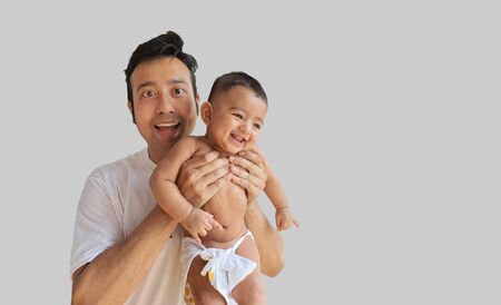 a smiling little baby boy held by his father with grey background and space for text