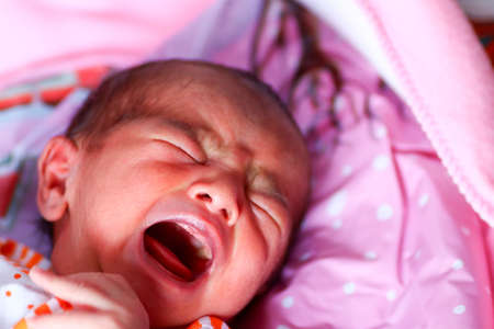 A newborn asian baby crying with open mouth and closed eyes.の写真素材