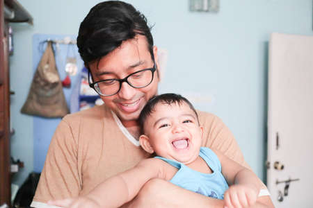 an infant toddler baby boy smiling on fathers lapの写真素材
