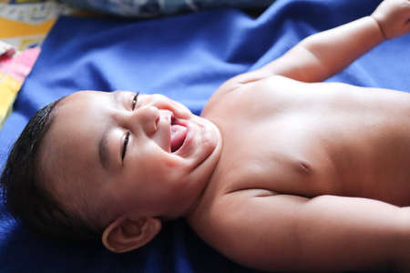 an infant toddler baby boy smiling on a blue towelの写真素材