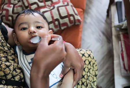 an infant toddler baby boy after weaning eating solid food with spoon
