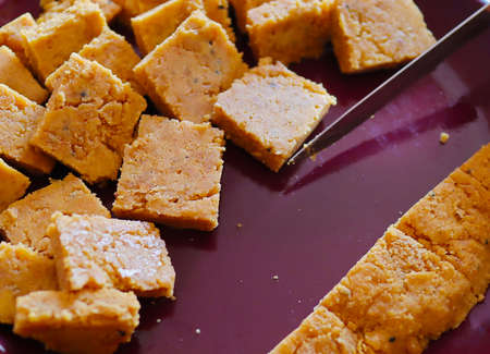 cakes of dal being cut in uniform pieces to cook dhoka r dalna a popular bengali vegeterian recipe