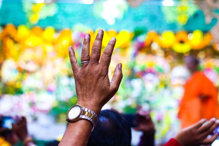 a devotee raising hands in a temple with blurred background and selective focusの写真素材