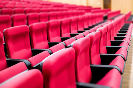 empty rows of seats of an auditorium with red reclining rows of seats and false ceiling led lightsの写真素材