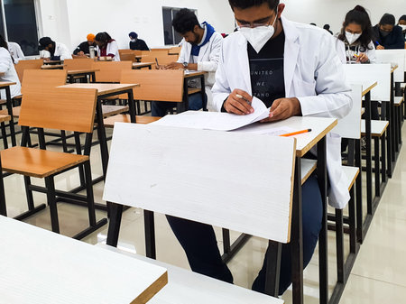 December 8, 2020.Lucknow Uttar Pradesh,India. West Bengal India. Medical students writing examination paper in mask maintaining social distancing at Radheshwam Medical College,Lucknow, UP, India.のeditorial素材