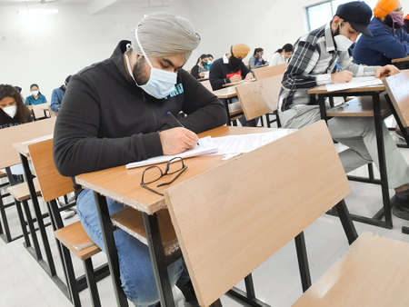 December 8, 2020.Lucknow Uttar Pradesh,India. West Bengal India. Medical students writing examination paper in mask maintaining social distancing at Radheshwam Medical College,Lucknow, UP, India.のeditorial素材