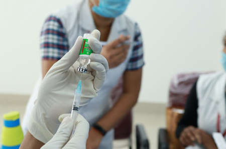 February 20,2021, Kishanganj, Bihar, India. Nursing staff holding used empty vials of Covishield vaccine with gloved hand after vaccination session at MGM Medical College, Kishanganj, Bihar.のeditorial素材