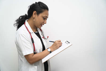 Hands of a doctor checking mobile phone in white coat and red stethoscope in white background.の写真素材