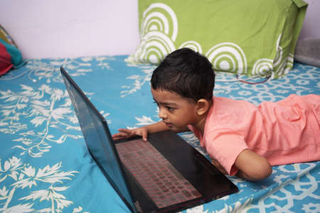 a toddler baby boy engaged in watching and exploring laptop.Screen time addiction concept image.の写真素材