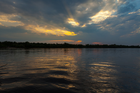 Sunrise over the lake with the reflection of bare trees in the waterの写真素材