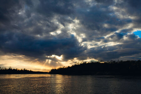 Sunrise over the lake with the reflection of bare trees in the waterの写真素材