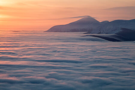 Peaks above clouds, winter mountains, foggy morningの写真素材