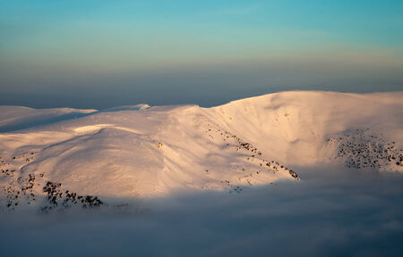 Peaks above clouds, winter mountains, foggy morningの写真素材
