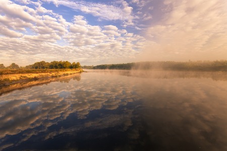 beautiful summer landscape misty morning on the river and clouds reflected in waterの写真素材