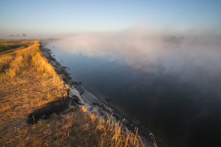 Fantastic foggy river with fresh green grass in the sunny beams. Dramatic colorful scenery. Ukraine,...
