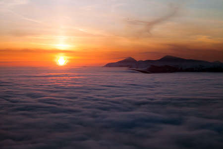 Peaks above clouds, winter mountains, foggy morningの写真素材