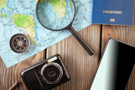 Preparation for Traveling concept, passport, smartphone, camera, map on a wooden background