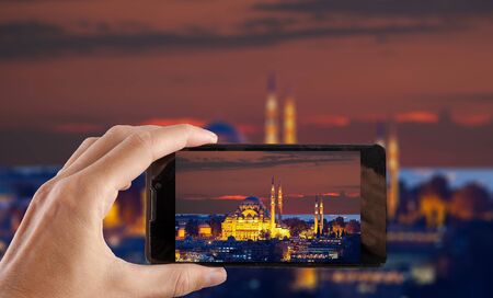 Travel concept. Hand making photo of night city with smartphone camera. Istanbul. Turkey