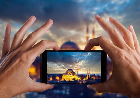 Travel concept. Hand making photo of night city with smartphone camera. Istanbul. Turkeyの写真素材