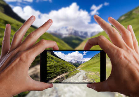 Travel concept. Hands making photo of Shkhara Glacier. Upper Svaneti, Georgia. Caucasus mountainsの写真素材