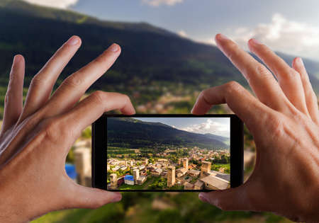 Travel concept. Hands making photo of Svaneti Old village in Georgia. Medieval tower. Mestiaの写真素材