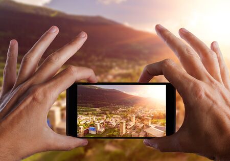 Travel concept. Hands making photo of Svaneti Old village in Georgia. Medieval tower. Mestia