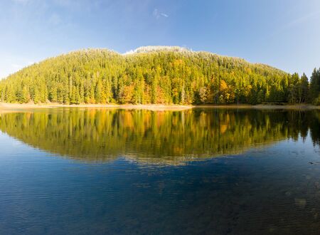 big lake in the middle of mountains during autumnの写真素材
