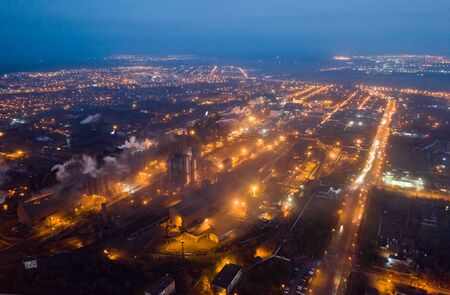 Aerial view. Emission to atmosphere from industrial pipes. Smokestack pipes shooted with drone. Night sceneの写真素材
