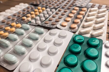 Closeup shot of different pills on table with tablets , pharmaceutical industry concept