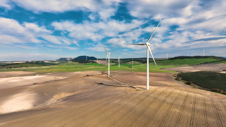 Wind power turbines generating clean renewable energy. Aerial view of windmills farm for energy production on beautiful cloudy sky at highland.の写真素材
