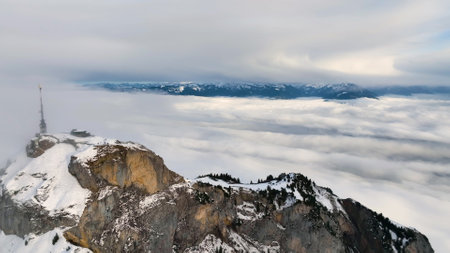 Aerial view of the cloudy and foggy Swiss Alps in Switzerland with snow on the peaks at sunsetの写真素材