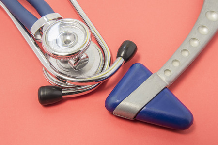 Medical diagnostic equipment for neurologist or doctor of internal medicine. Stethoscope or phonendoscope with blue neurological reflex hammer lying on red background or table in doctor's officeの写真素材