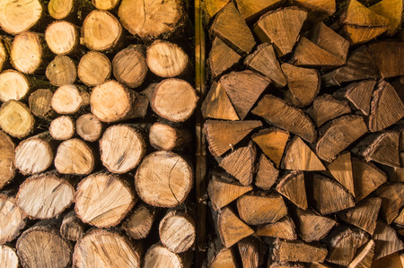 Round and triangular cutted or chopped firewood, folded in stacks in the storage, ready to use in...