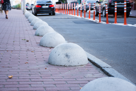 Car or motor vehicle stop security barriers or hemispheres bollards. Concrete structures to prevent parking on the sidewalks are placed at the edge of the roadway for carsの写真素材