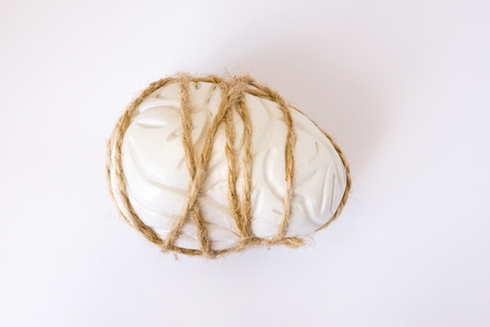 Anatomical model of human brain, strongly tied around with rope on white background. Visualization compressing throbbing headache, migraine, diseases of brain, accompanied by headache idea for photoの写真素材