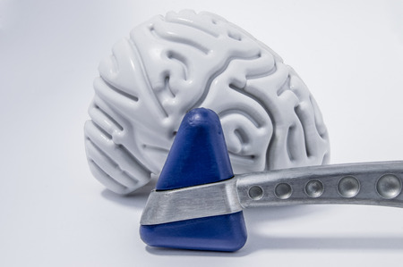 Neurological reflex hammer stands in front of the figure of the human brain on a white medical table...