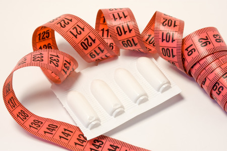 Laxatives rectal suppositories in package and measuring tape around. Using laxatives medicines for weight loss and treating obesity concept photo. Alternative pharmacological methods to weight lossの写真素材
