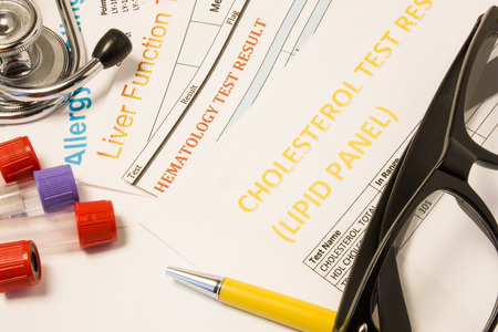 Clinical trial research concept photo. Results of clinical medical laboratory tests: blood, allergy analysis, cholesterol and lipids, liver function, lie next to test tubes, stethoscope and glassesの写真素材