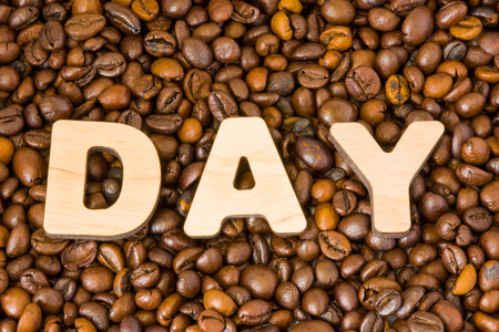 Word of Day composed of large wooden letters on background of roasted brown coffee beans.の写真素材
