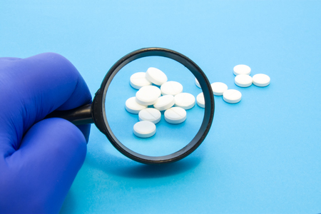 Pharmacist or expert on pharmaceutical inspection identifies pills. Testing, verification and determining pharmaceutical counterfeiting or fakes of medicines and medicinal substance quality conceptの写真素材