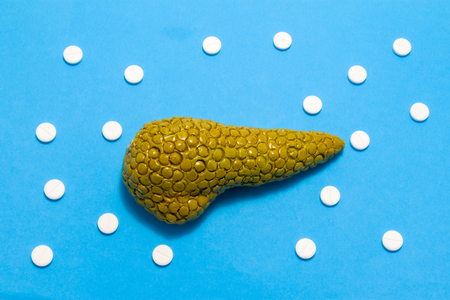 3D anatomical model of pancreas gland is on blue background surrounded by white pills as ornament polka dots. Medical concept by pharmacological tableted treating of pancreas disease, pharmacotherapyの写真素材
