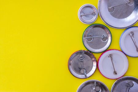 Inverted metal badges with clasps on yellow uniform background view from above with the clear area of half photo for labels, headers. Concept photo for prizes, souvenirsの写真素材