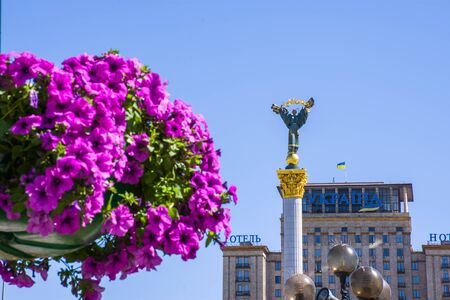Statue of the Berehynia on the Independence Square in the background in focus and blurred flowers in the foreground as a symbol of spring in Kyiv and Ukraineのeditorial素材