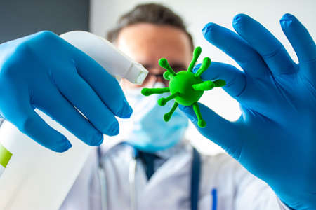 Antiseptic against pathogen viruses. Doctor or scientist are holding in one hand model of a...