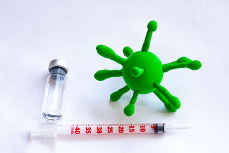 A doctor in the background with a vaccine and syringe in one hand and a model of the virus in the other. Idea or concept photo for vaccination against bacterial and viral respiratory diseasesの写真素材