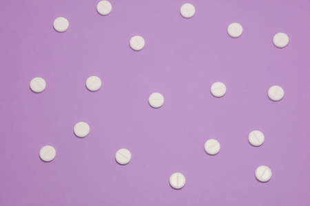 White pills on purple background. Top view. Flat lay. Copy space.の写真素材