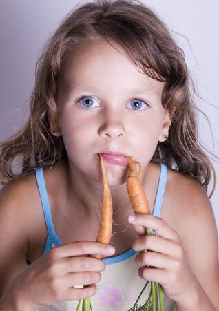 A little girl holding in her hand a carrotの写真素材