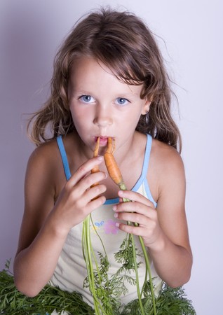A little girl holding in her hand a carrotの写真素材